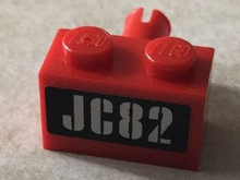 Part 2458pb01 - Brick, Modified 1 x 2 with Pin with Silver 'JC82' on Black Background Pattern (Sticker) - Set 76006 - De BrickPlaats