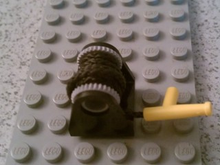 Part 2584c09 - String Reel 2 x 2 Holder with Light Bluish Gray Drum with Black String 35L with Yellow Hose Nozzle Simple (2584 / 2585 / 194cx2) - De BrickPlaats